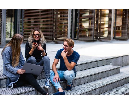 Des étudiants sont assis à l'extérieur et échangent