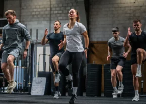 Groupe de stagiaires réalisant un exercice de montées de genoux dynamiques lors d'un cours collectif en salle de cross-training