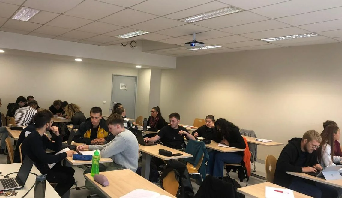 Étudiants IPMS en travaux de groupe dans une salle de cours moderne et lumineuse.