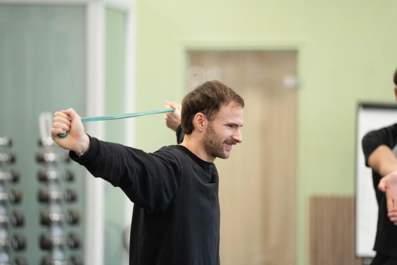 Stagiaire réalisant un exercice d'écartés avec bande élastique de résistance en salle de musculation
