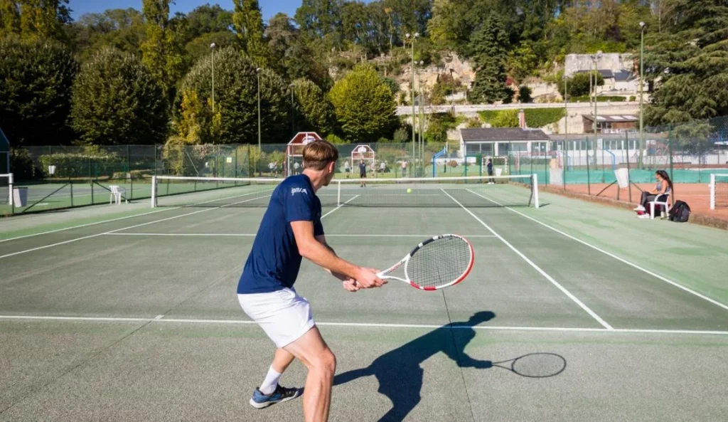 Stagiaire IPMS en pratique tennistique sur court extérieur.