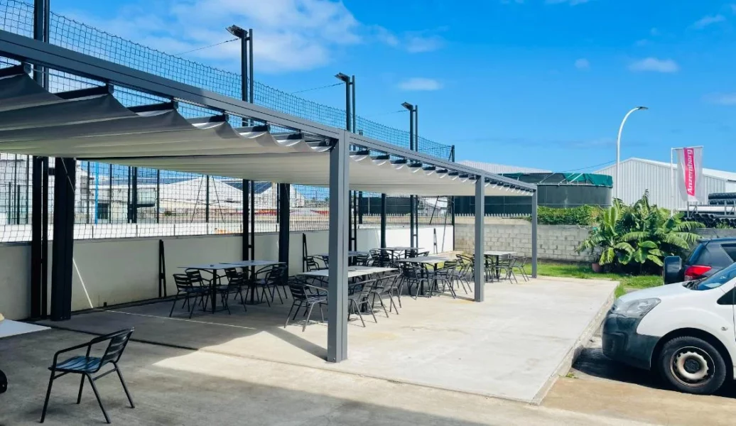 Terrasse extérieure couverte IPMS Saint-Louis avec tables et chaises sous pergola.