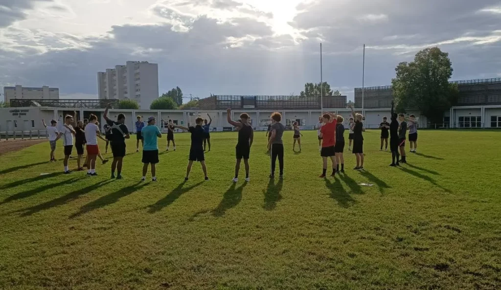 Séance BPJEPS APT à l’IPMS Bordeaux : étudiants en échauffement sur terrain de sport en plein air.