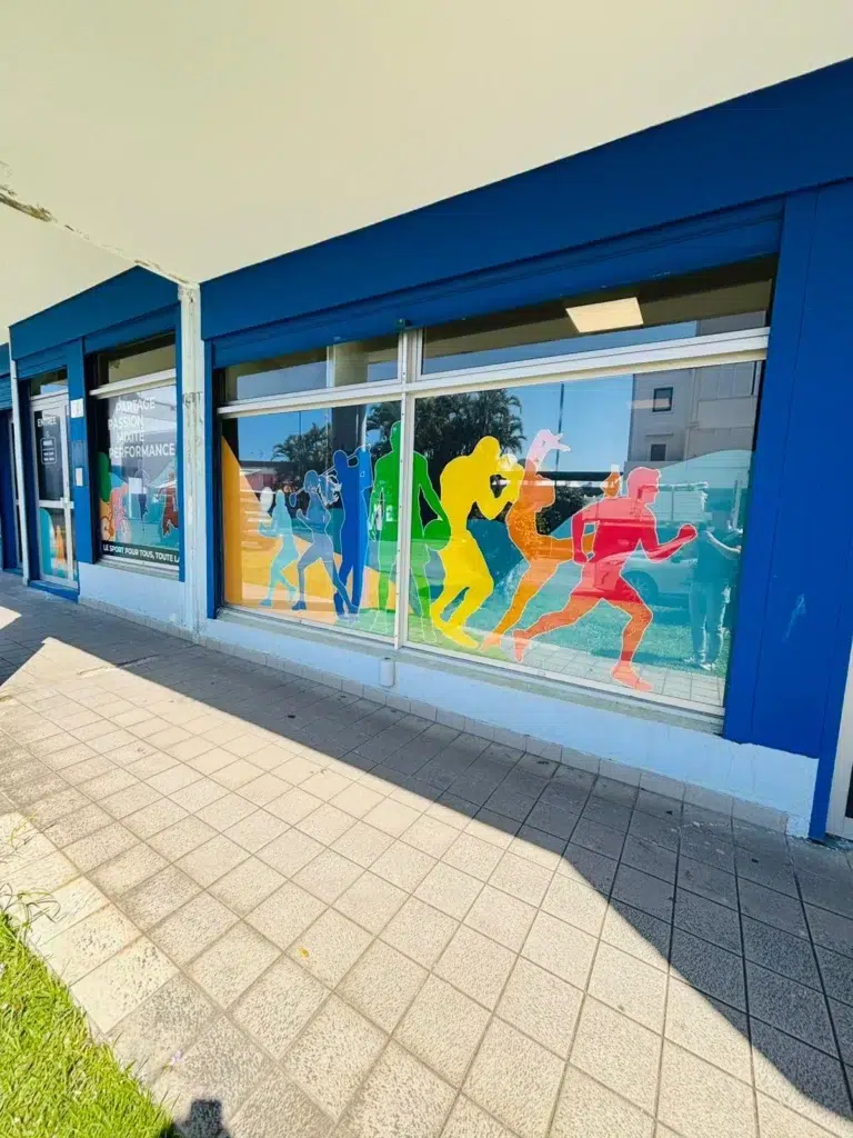 Façade du campus IPMS Saint-André avec vitrophanie colorée représentant des sportifs.