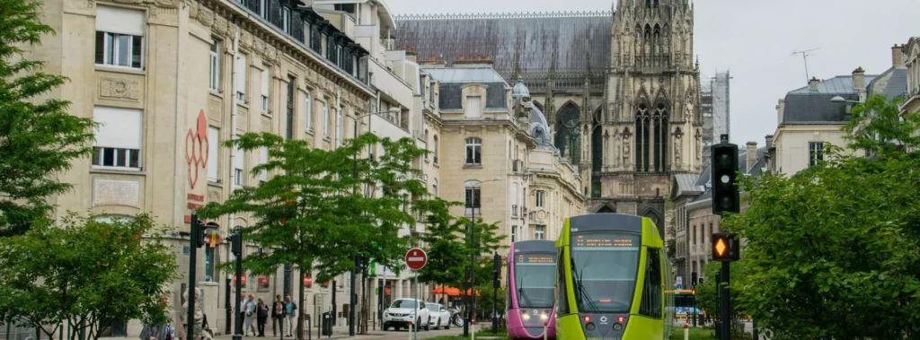 Vue urbaine de Reims, tramway vert et cathédrale en arrière-plan.
