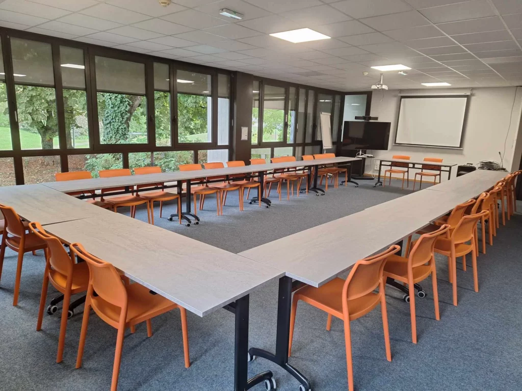 Salle de classe moderne IPMS Reims avec tables en U et chaises orange.