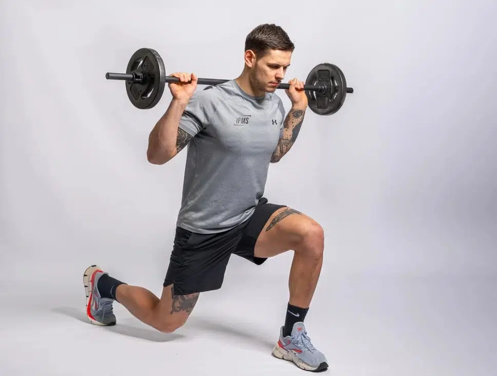 Stagiaire IPMS réalisant une fente avant avec barre chargée sur les épaules en position parfaite