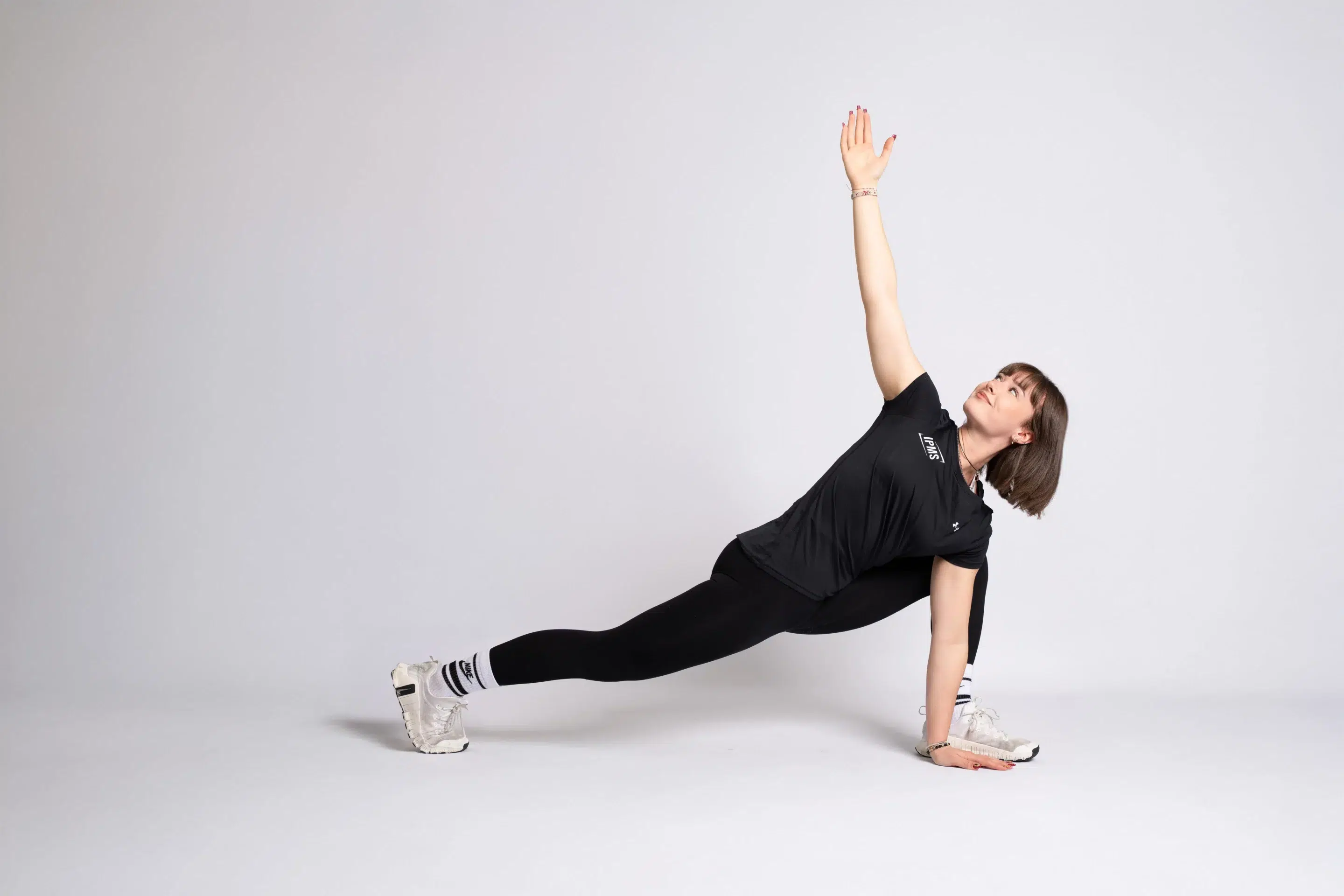 Stagiaire IPMS en tenue noire réalisant une fente basse avec rotation et bras tendu vers le ciel