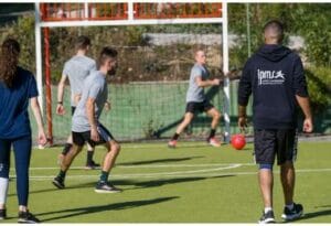 Formateur IPMS encadrant une séance de football sur terrain synthétique avec des stagiaires BPJEPS MAPST