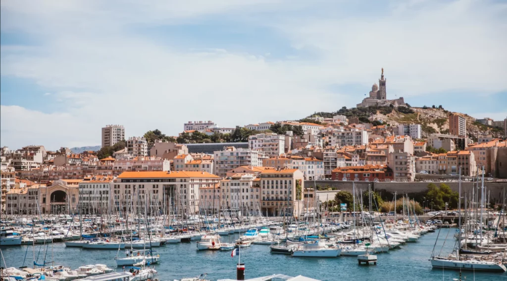 Panorama urbain de Marseille avec le Vieux-Port et Notre-Dame-de-la-Garde sous un ciel dégagé.