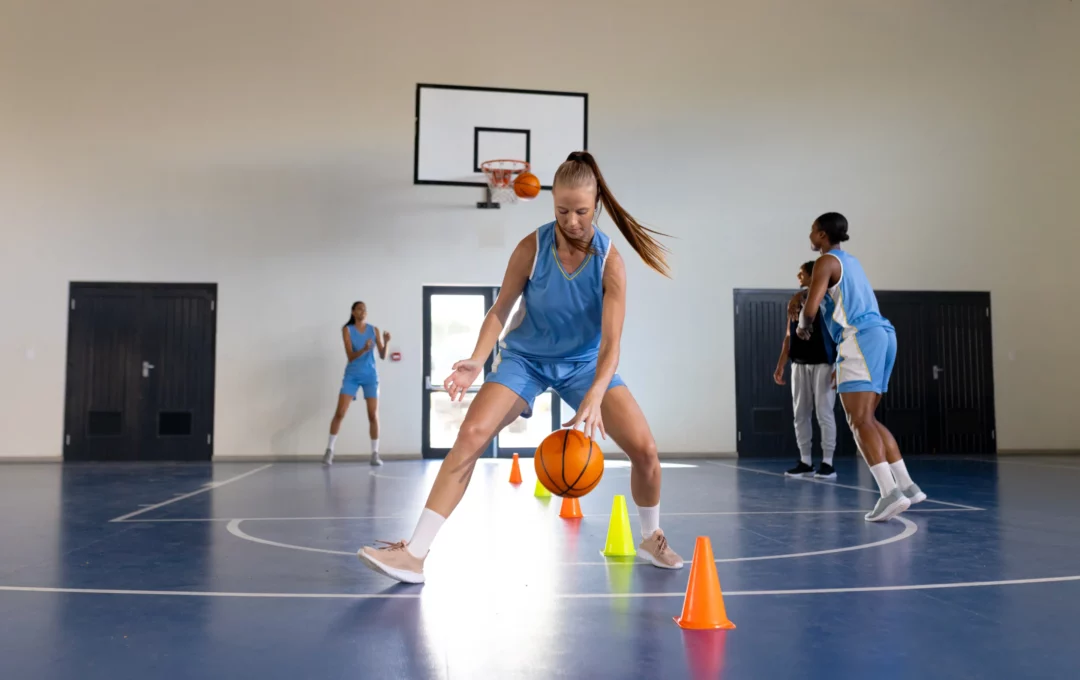 Joueuse travaillant le dribble entre cônes lors d’un entraînement de basketball en gymnase.