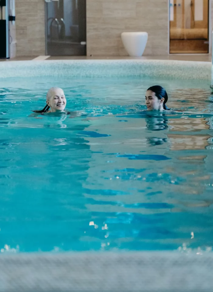 Séance aquatique en piscine intérieure : une stagiaire accompagne une nageuse, illustrant la pratique du futur maître-nageur.