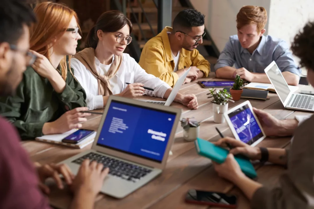 Groupe d’étudiants en formation IPMS travaillant en équipe autour d’ordinateurs portables et de tablettes.