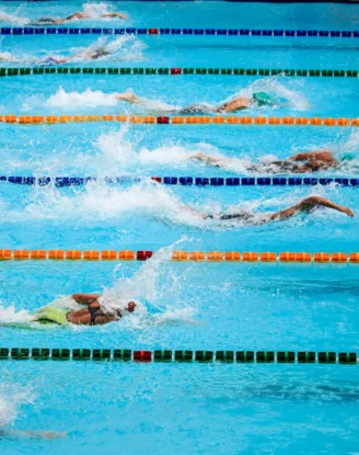 Compétition de natation en piscine municipale : nageurs en crawl sur plusieurs couloirs.